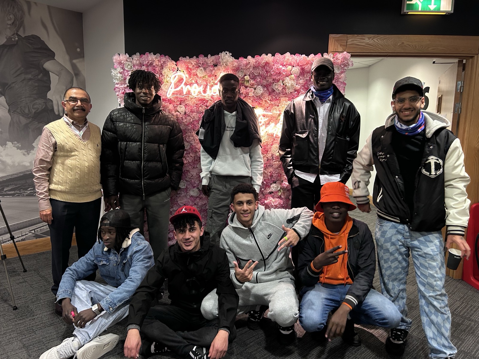 Diverse group of young people posing at the Proud to be Me flower wall
